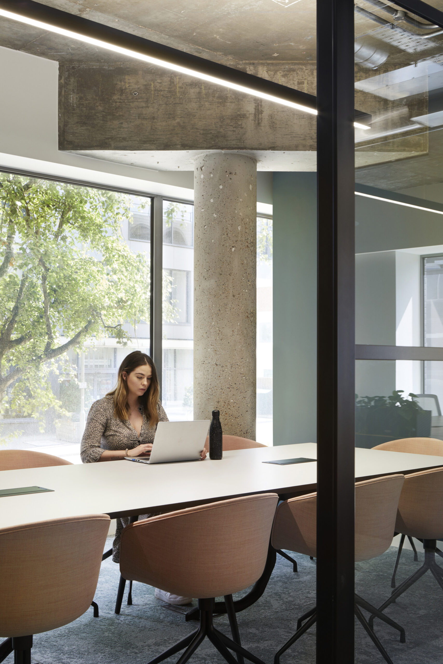 A woman sat down in a meeting room working on her laptop, at Forge