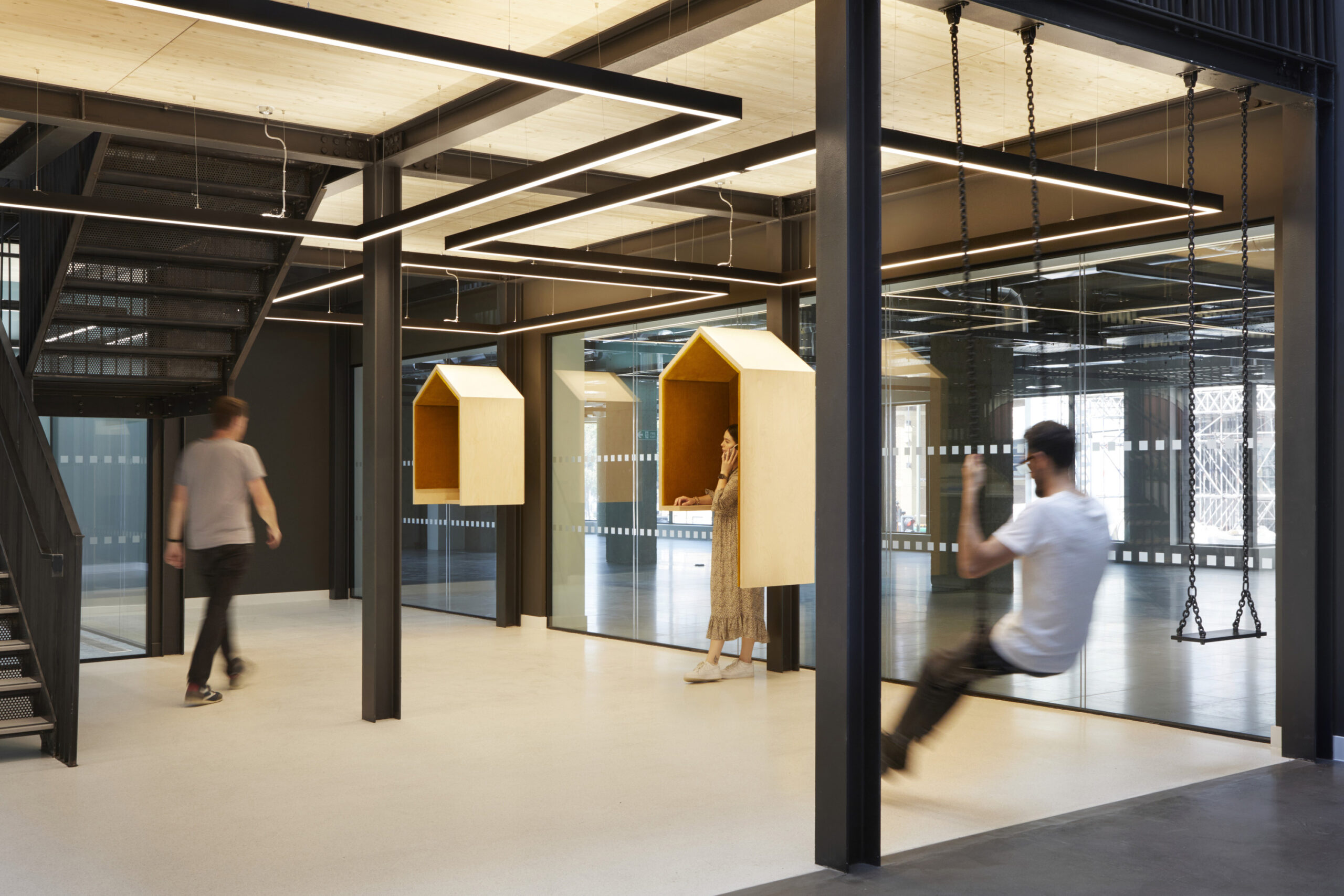 People hanging out in a break out area, featuring swings and huts, in the Forge building.