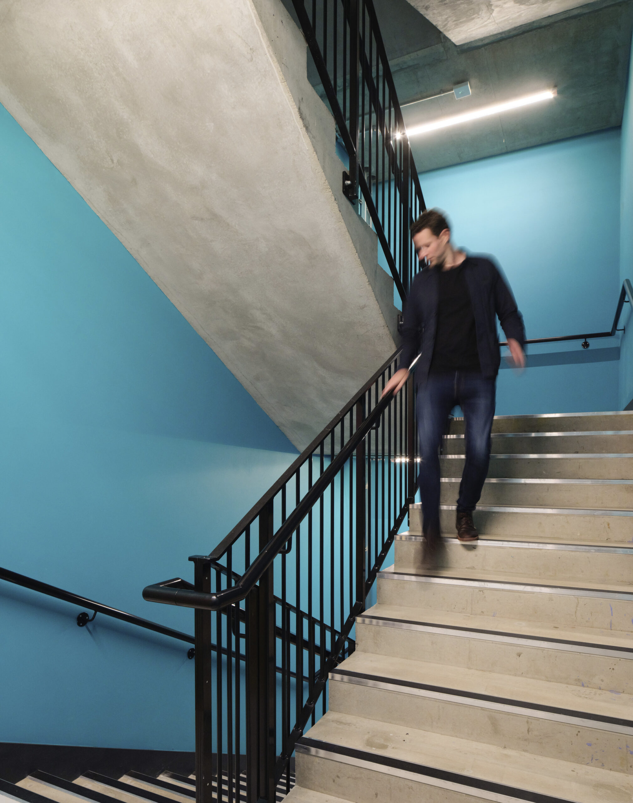 Man walking down blue stairs at the Leeds Beckett University School of