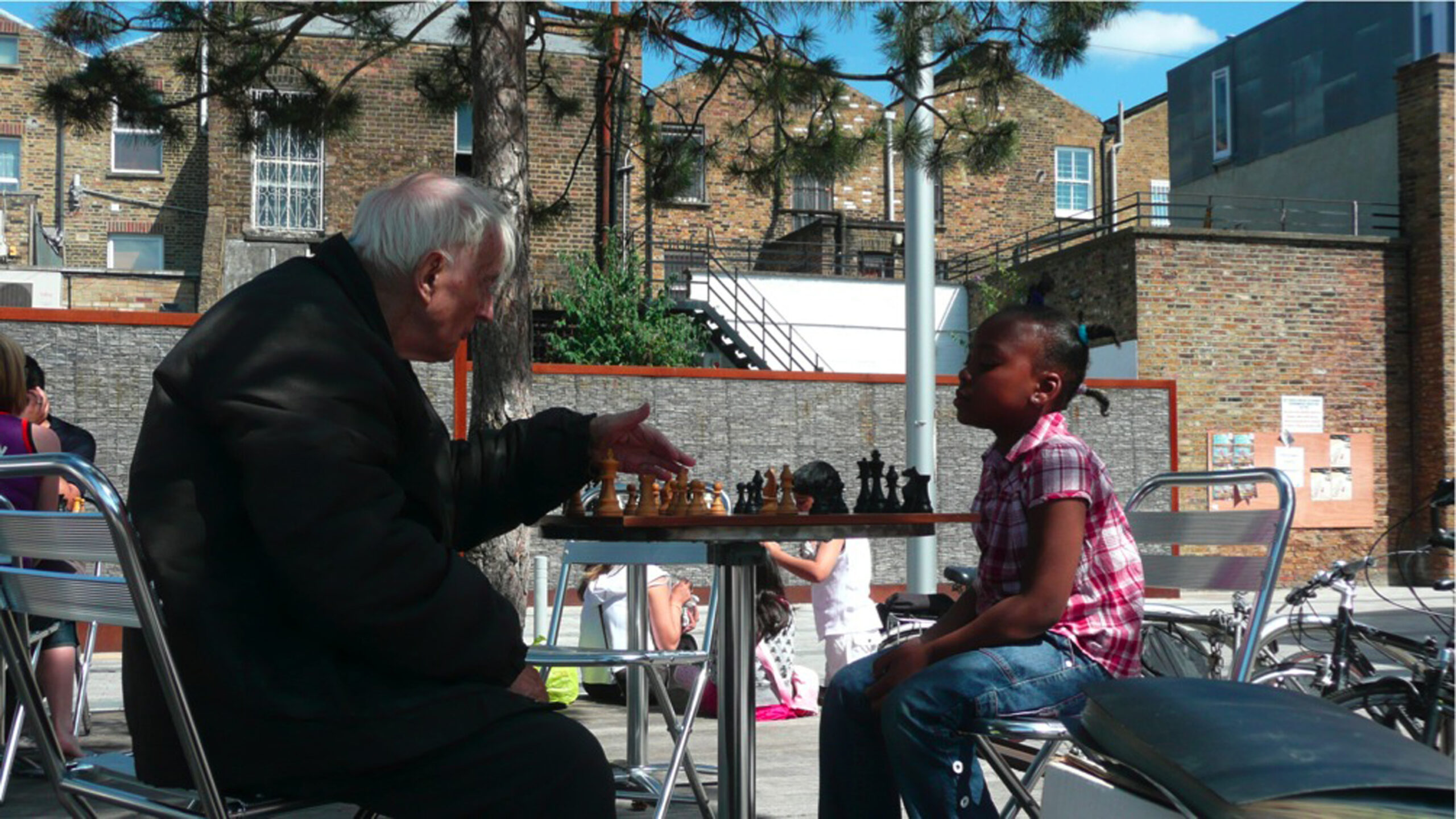 And older man and young child sat down and playing chess in Gillett Square