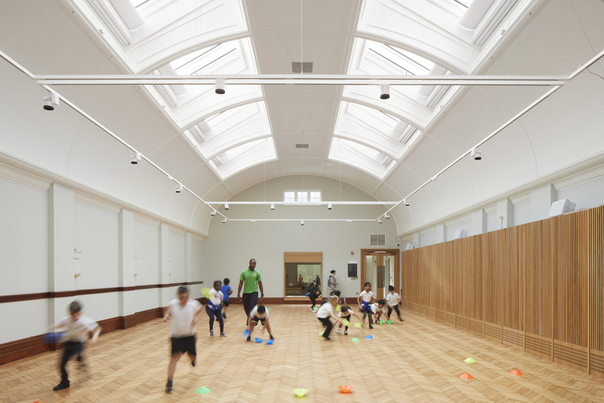 Children playing sports games with colourful cones in a studio.